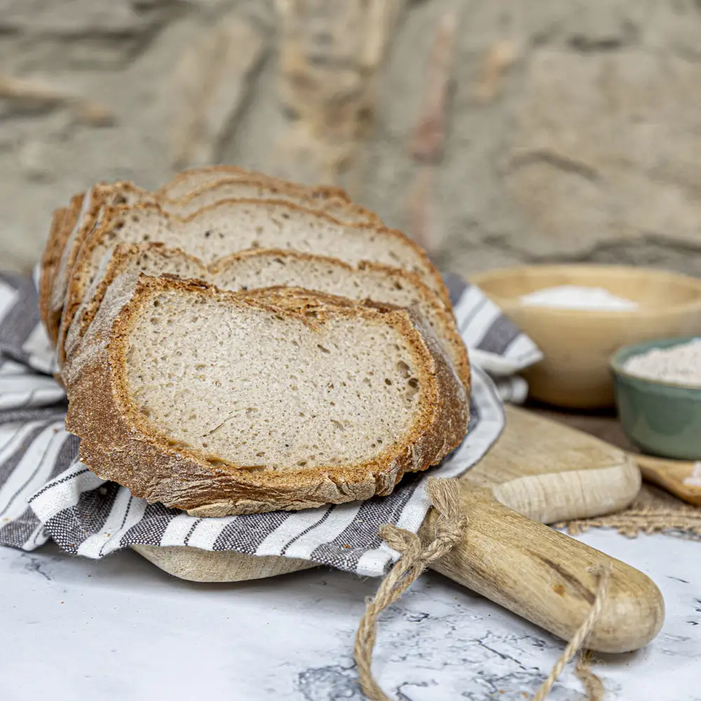 Rebanadas de pan de trigo sarraceno sin gluten sobre tabla de madera, con miga esponjosa y corteza rústica, pan artesanal saludable